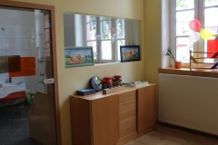 Ein Sideboard mit Spielzeug unter einem Fenster, das in den Wacshraum zeigt, und einer Glastür, die zum Waschraum führt.