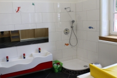 Ein heller Wacshraum mit Dusche und Kinderwaschbecken.
