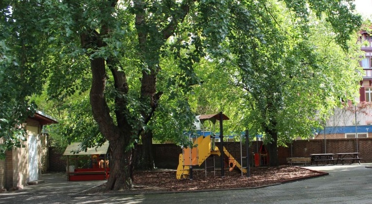Ein HOf mit Spielplatz und Bäumen